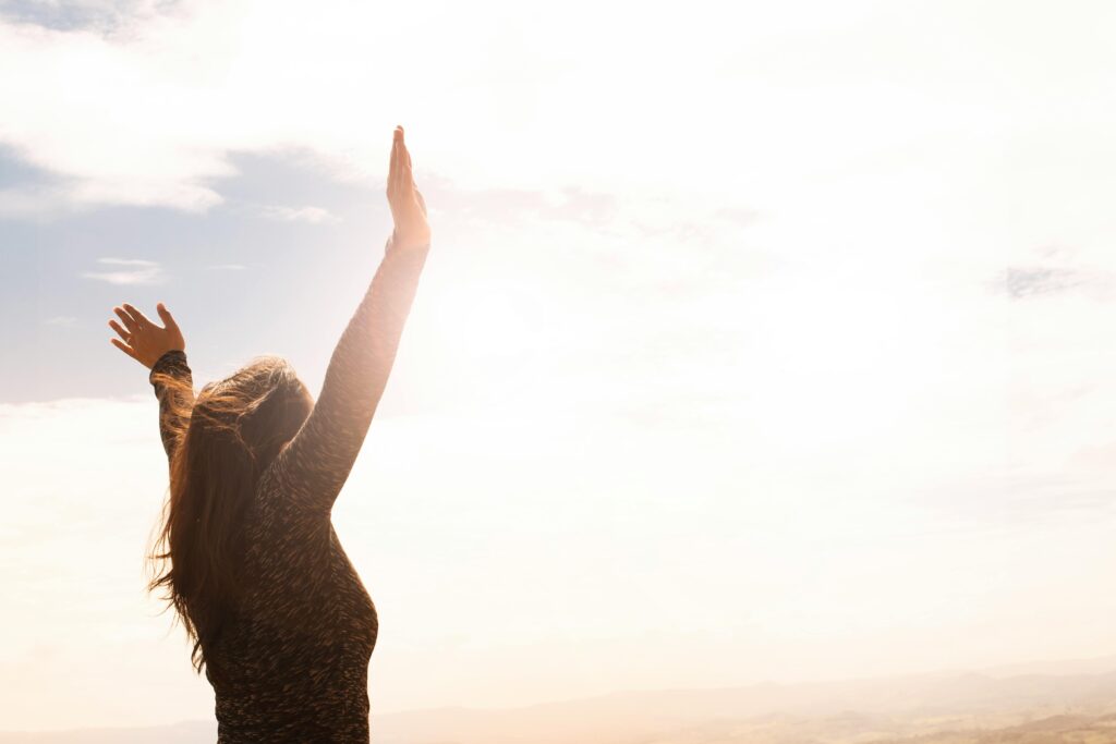 Woman waving hands in air toward the sky.